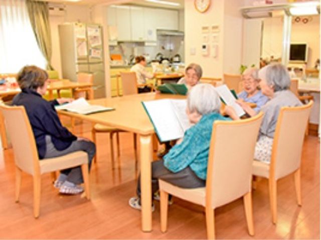 笑顔の集いの食堂空間 レクリエーション 明るく開放的な食堂で、利用者同士が椅子に座り交流を楽しんでいます。共有スペースでのコミュニケーションが活気にあふれています。