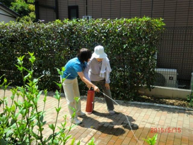 散歩する二人の姿 消火訓練 暖かい日差しの下、スタッフと一緒に安全に外散歩をする様子は、穏やかな日常を感じさせます。
