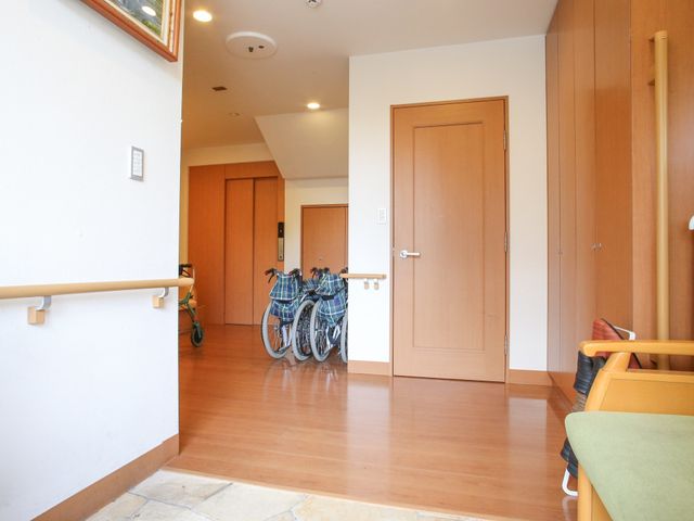 廊下と車椅子 入口スペース 手すりが設置された清潔感のある廊下です。安心してお過ごしいただける環境を整えています。