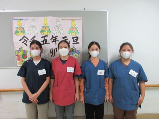 マスク姿の職員4人掲示物前  