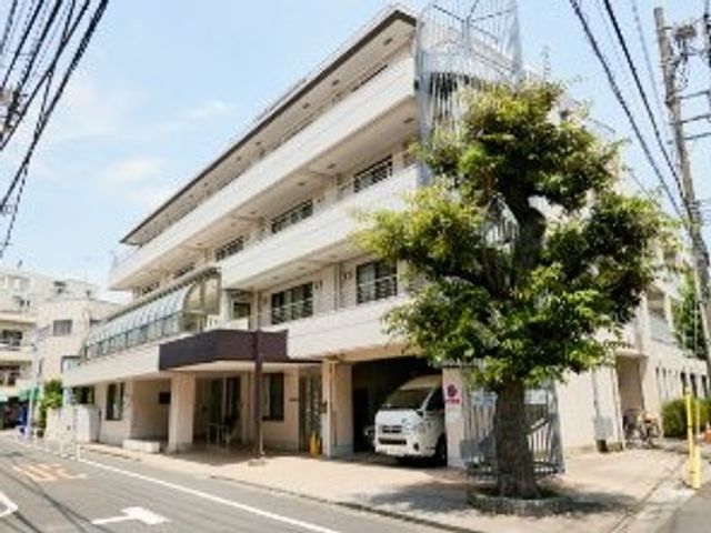 三階建ての建物外観 外観   明るい外壁とバルコニーが印象的な建物です。車の出入りもしやすそうな前面スペースがあり、働く場の雰囲気が伝わります。