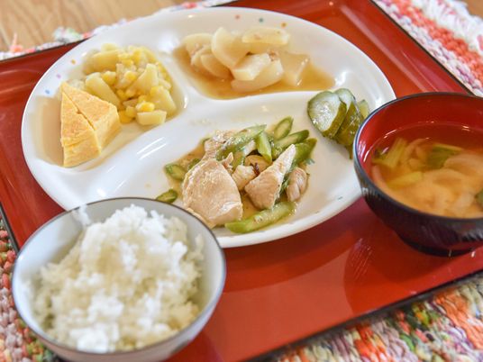 食事の一例のクローズアップ写真。鶏肉とアスパラの炒め物。や卵焼き、大根の煮物、お味噌汁など、柔らかく食べやすいメニュー。