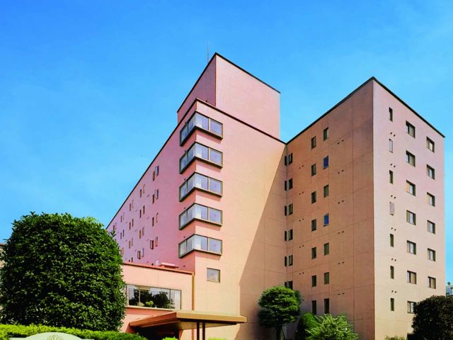 施設の落ち着いた外観 外観 ピンク色の壁が特徴的な落ち着いた雰囲気の建物です。緑が美しく手入れされた周囲の景観と調和しています。