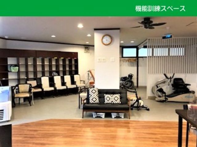 機能訓練スペース 機能訓練室   木目の床が広がる明るい空間で、椅子や運動器具がゆったり配置されています。リハビリや体を動かす場として使いやすそうです。