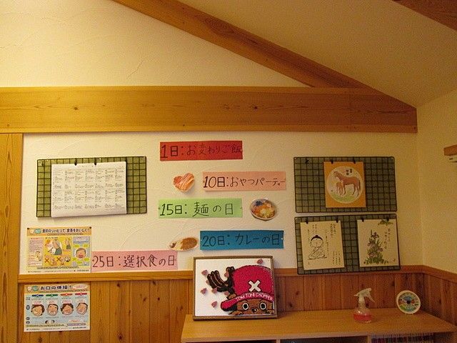 掲示物のある廊下 掲示物   食事の予定や行事をわかりやすく掲示した壁面です。利用者さんに日々の楽しみが伝わりやすい工夫が見られます。