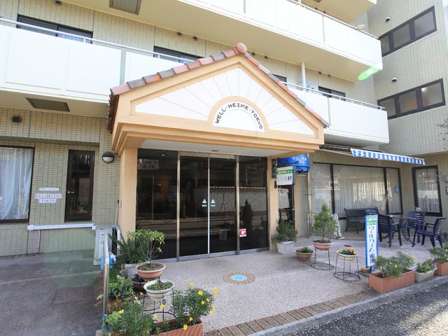 明るいエントランス風景 外観 庭木や植木鉢が飾られた清潔感のあるエントランスです。来訪者を優しく迎える雰囲気が感じられます。