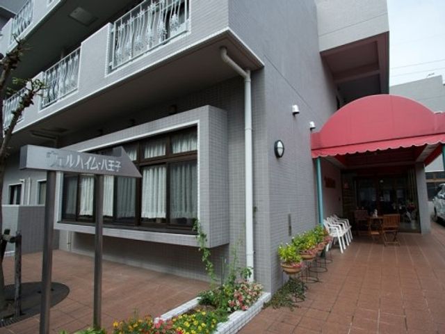 屋外のエントランスと看板 入り口 アットホームな雰囲気の入口に花が飾られ、歓迎感が漂います。