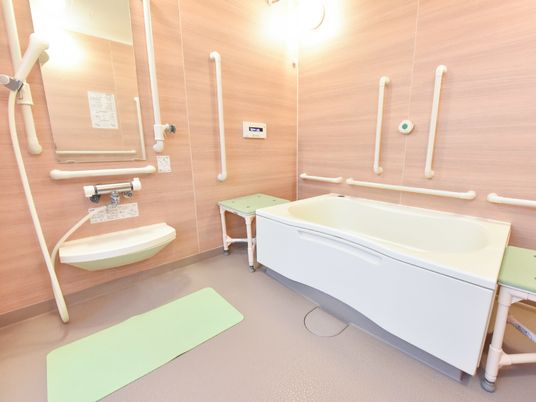 木目調の室内が暖かみのある浴室である。浴槽は一体型ではなく独立型となっているため短辺方向に介助用椅子を置くことが出来る。