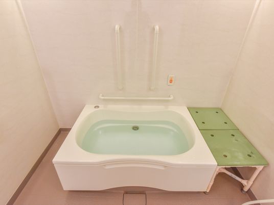 大きな白い浴槽が、中央付近に設置されている。その右側には、壁との隙間を埋めるようにモスグリーンの椅子が置いてある。
