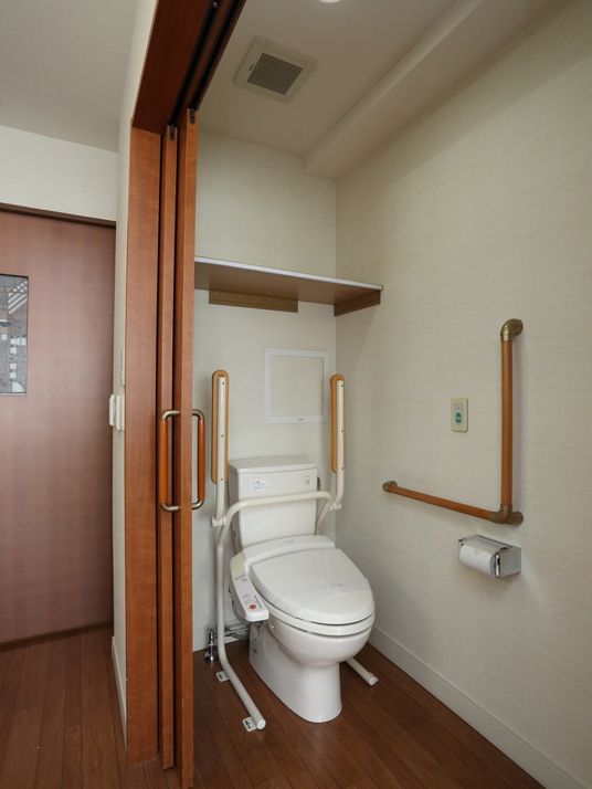 トイレには洗浄機能付きの便座が完備されており、各所に手すりが設置されている。壁にはナースコールが取りつけられている。