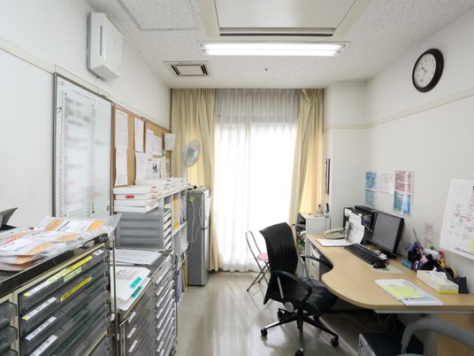 医師が問診をするための机があり、パソコンや問診表などが置かれている。天井には空調と換気口が設置されている。