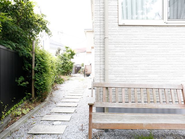静かな庭の木製ベンチ きれいに整備されて敷地 緑豊かな小径に面したベンチで、読書やお話し相手を待つ穏やかな時間を過ごせます。