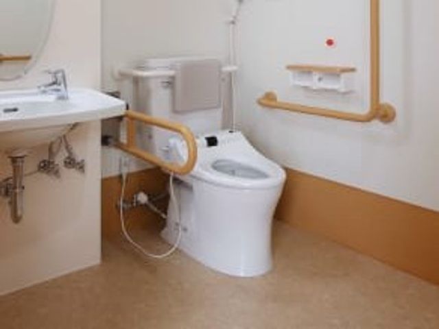 手すり付きのトイレ トイレ   手すりが設置された明るいトイレです。洗面台も近く、使いやすさに配慮された空間です。