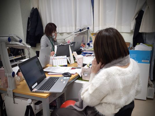 スタッフが机で電話応対する事務室  
