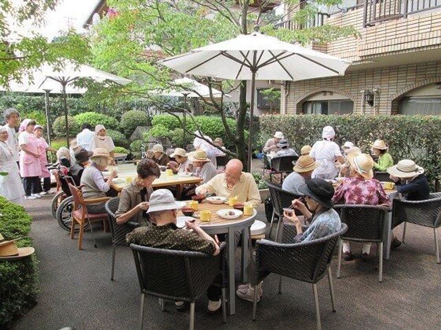 屋外で食事を楽しむ人々 お食事会 緑豊かな中庭で、穏やかなひと時を過ごす笑顔の集い。
