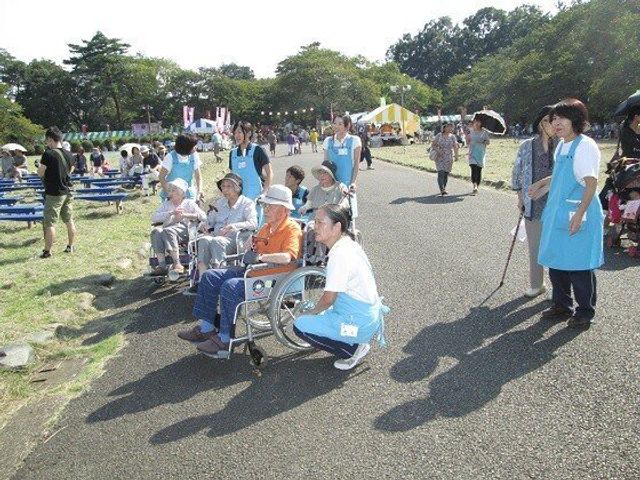 イベント参加する利用者とスタッフ レクリエーション 明るい笑顔のスタッフが利用者の方々をサポートして、イベントを楽しんでいる様子です。