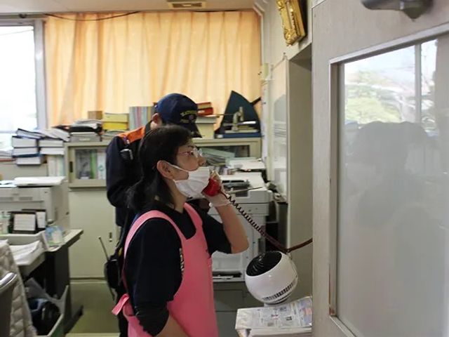 スタッフが電話する事務室 内観   書類や機器が並ぶ事務スペースです。スタッフの連携や連絡の様子が伝わり、就業時の動きがイメージしやすいです。