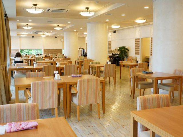 やすらぎの食堂空間 ダイニング ゆったりとした食堂で明るく開放的な雰囲気を体感してください。後方にいる一人の方が静かに食事を楽しんでいます。