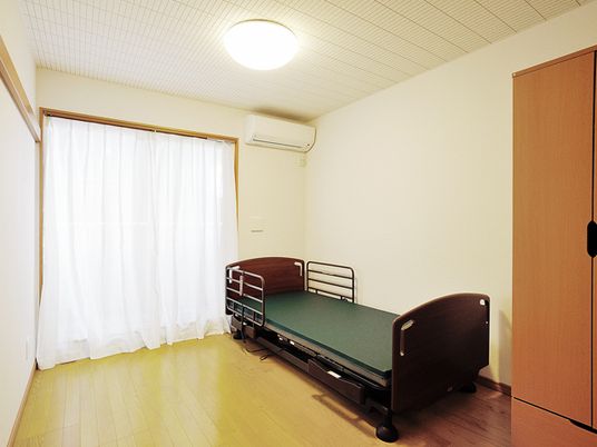 ベッドとエアコン、収納がついた施設内の居室の様子。ワンルームタイプの部屋