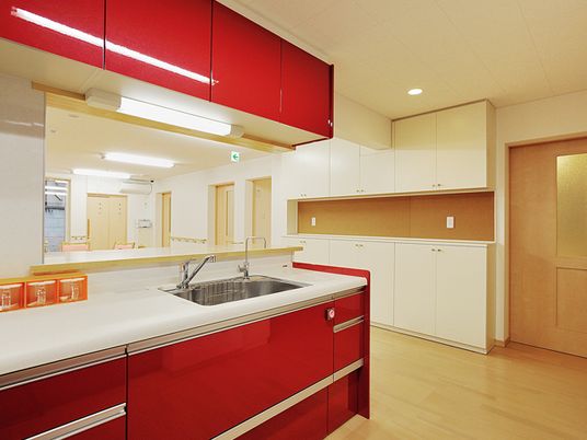 レッドを基調にしたモダンなデザインのキッチン。施設内のキッチンスペース