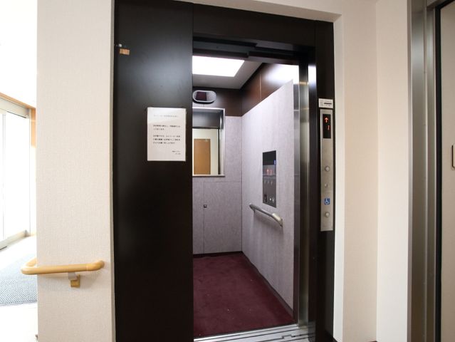 エレベーターの開いた扉 エレベーター ゆったりとした空間のエレベーターです。手すりや大きなボタンがあり、どなたでも安心して利用できます。