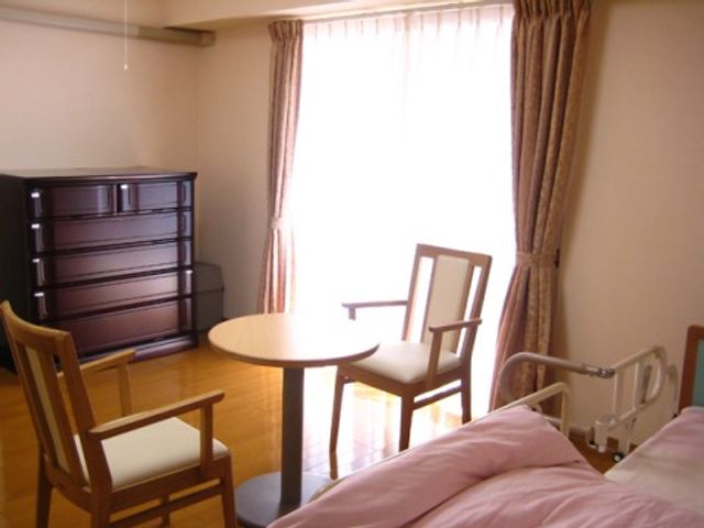 明るい居室の一角 居室 陽光がたっぷりと差し込む、清潔感のある部屋です。個人のスペースを大切にしながら、快適な時間を過ごせます。