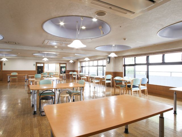 広々とした明るい空間 共有スペース 天井が高く大きな窓が特徴の、ゆったりとした食堂です。明るく開放的なこの場所で、美味しい食事とくつろぎの時間をご提供しています。
