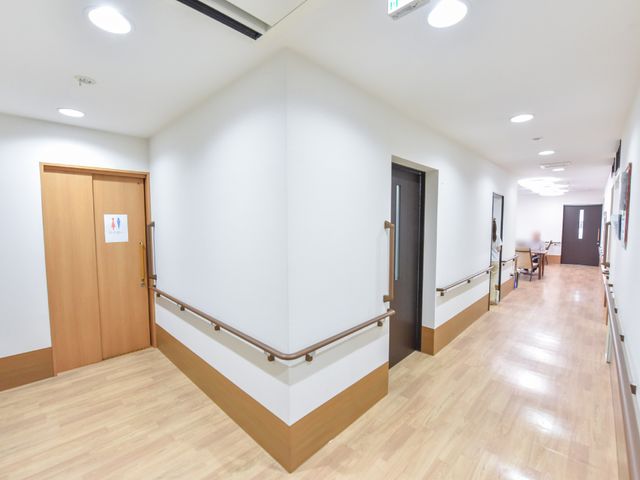 清潔感のある廊下 共用スペース 手すり付きの廊下は清潔感があり、壁には掲示物が配置されています。働く環境としても居心地がよさそうです。