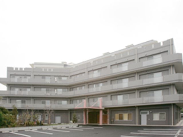ゆったり感のある施設外観 外観 広々とした駐車場があり、四階建ての落ち着いた色合いの建物です。周囲には自然が残り、穏やかな環境が広がっています。