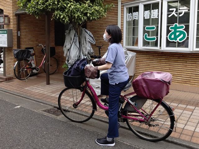 訪問看護の様子 外観 訪問看護に取り組むスタッフの姿をご覧いただけます。自転車での移動も特徴的です。