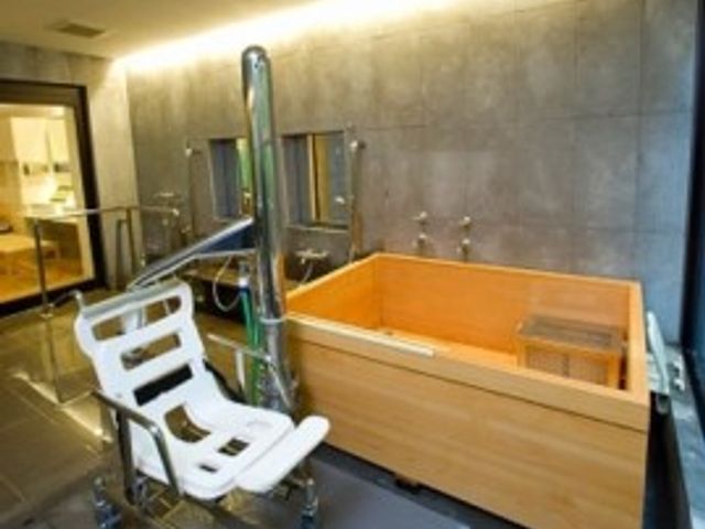 バリアフリー設計浴室 ヒノキ浴槽 木材を使ったやわらかい雰囲気の浴槽と、移動をサポートする椅子が設置された設備の整った浴室です。安心してご利用いただける環境が整っています。