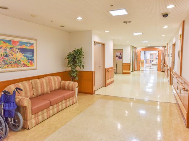 廊下にソファと植物 廊下 ゆったりとしたソファが設けられた明るく清潔な通路です。壁には絵画が飾られ、落ち着いた雰囲気の中で一息つけるスペースがあります。