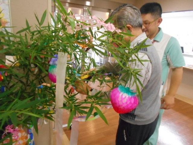 活動を楽しむ利用者とスタッフ イベント 利用者がスタッフの支援を受けながら、室内の飾りつけに参加しており、和やかな雰囲気です。ここではさまざまな創作活動が行われています。