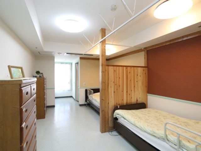 清潔感ある居室の様子 居室（相部屋） 広々とした部屋で、木の温もりが感じられる落ち着いた空間です。快適な生活を支援するための家具も整っております。
