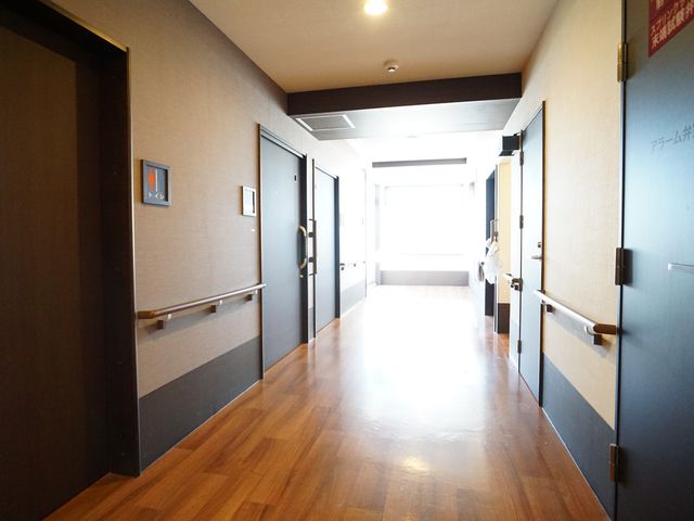 木目調のきれいな廊下 廊下 手すりが設けられた落ち着いた色合いの廊下です。床の木目調が空間に温かみを与えています。