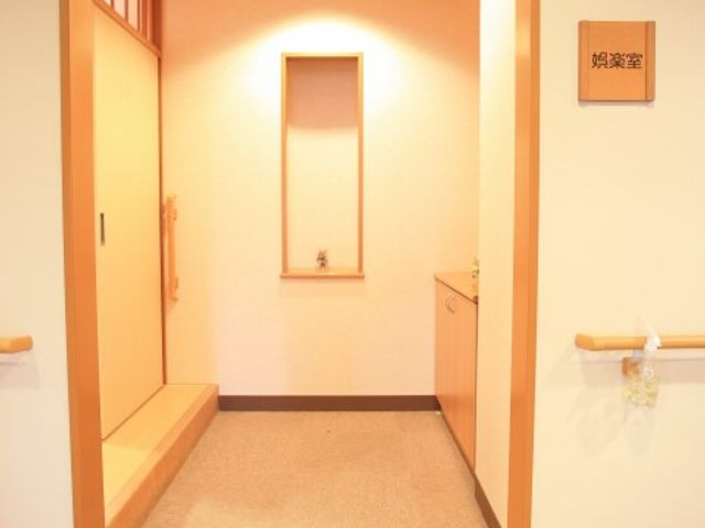 落ち着いた色合いの廊下 娯楽室 清潔感のあふれる廊下は、訪れる皆様をやすらぎの空間へと誘います。明るく穏やかな雰囲気が、日々の活動を支えます。