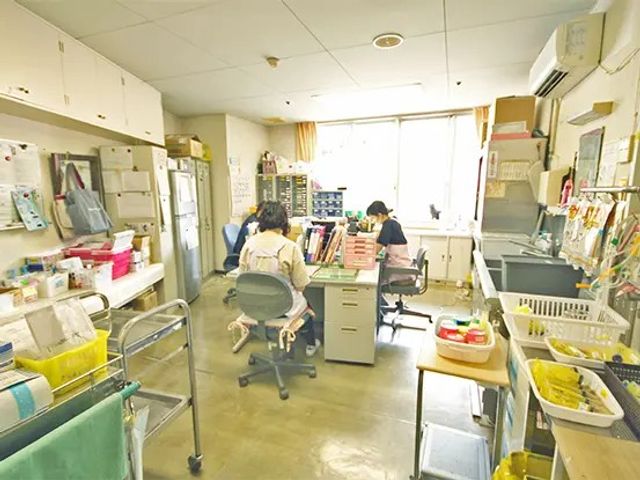 スタッフ作業室 内観   窓から光が入る明るい作業スペースです。机が並び、スタッフの方が落ち着いて作業しやすい様子が見られます。