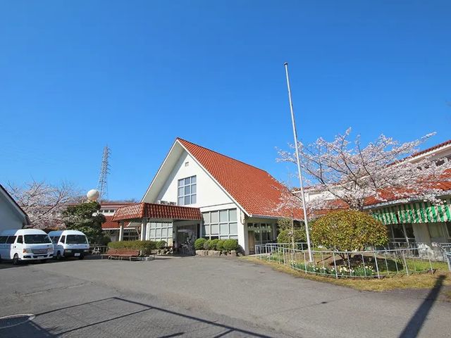 桜咲く施設の外観 外観   赤い屋根と白い外壁が印象的な建物です。桜が咲く季節の落ち着いた雰囲気で、働く環境をイメージしやすいです。