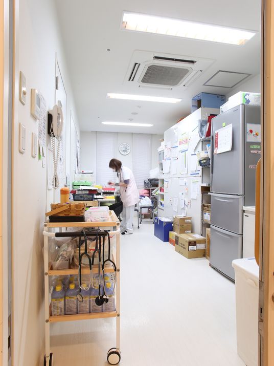 施設の写真 病院の診察室のようなイメージの部屋で、聴診器などの機器がある。インターホンや大きな冷蔵庫が設置されている。