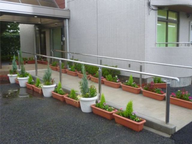 エントランスの緑化スペース 玄関 緑豊かな植物が並ぶエントランスは、温もりと安らぎを感じさせる空間です。訪れる方々をやさしく迎え入れます。