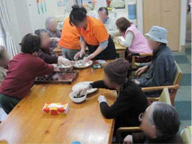 活気ある共有スペース 日常 スタッフが丁寧にサポートしながら、皆で食事の準備をしています。このような協力の場は、コミュニケーションの活性化にも寄与しています。