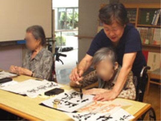 書道を行う利用者と職員