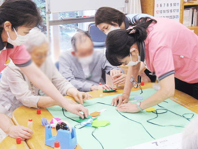 手作業を楽しむ風景 多目的室 利用者とスタッフが一緒に、手作業を楽しんでいます。共同での活動が活発な環境です。