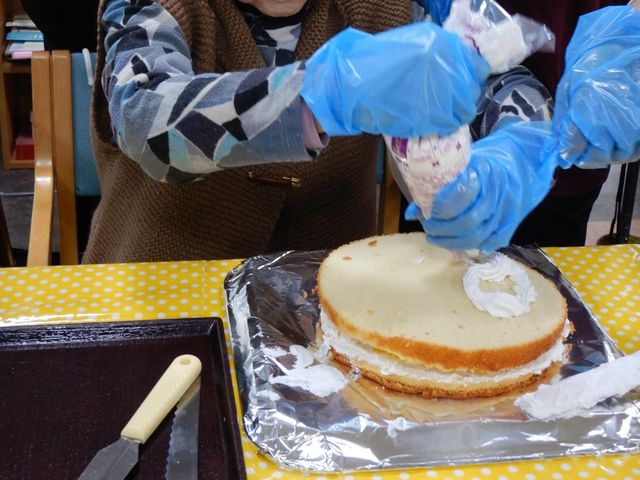 手作りケーキ作り体験 多目的室 手先を使った活動に参加されている方がいます。ケーキ作りを通じて、楽しいひと時を過ごしていらっしゃる様子が伺えます。
