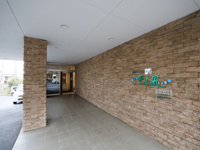 エントランス壁面と看板 玄関 自然な風合いの壁面に設えられた、明朗で安心感を与える入口です。快適な出勤を迎えることができ、働きやすい環境が整っています。