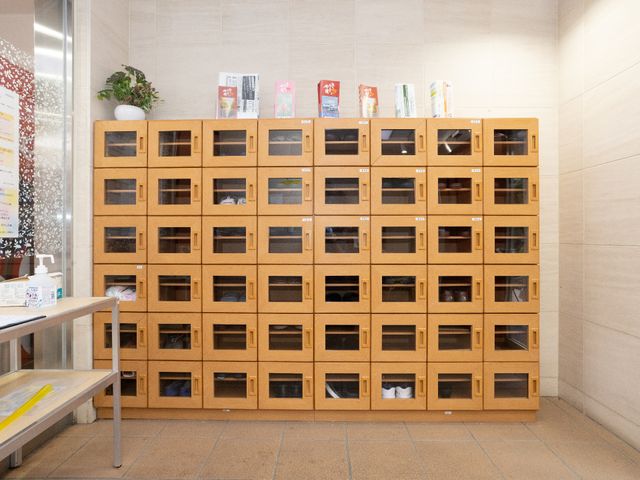 整理された木製の棚 玄関 清潔感があるエントランスには、個人の荷物を収納する木製の棚が配置されており、スタッフの整理整頓への気配りが感じられます。