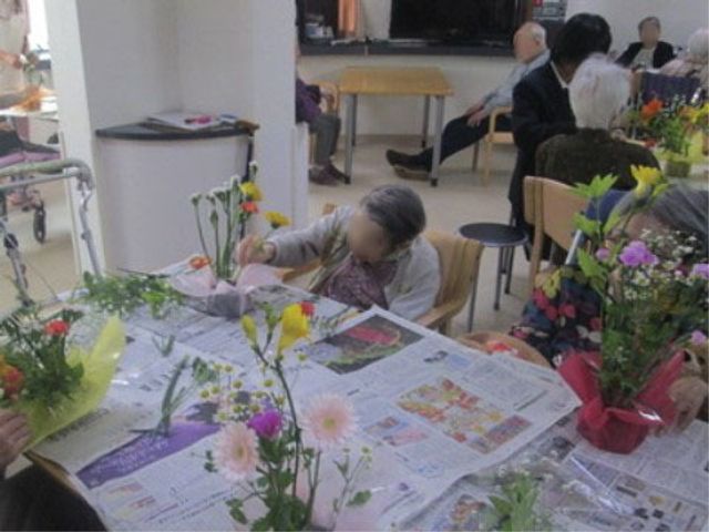 花を活けるレクリエーション イベント 手先を使って花を活ける様子が見受けられる、温かい雰囲気の多目的スペースです。ちょっとした趣味活動にぴったりの環境が整っています。
