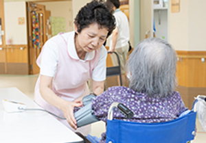 血圧測定する介護士と入居者
