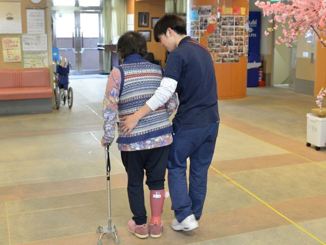 利用者とスタッフの廊下 廊下 支え合うスタッフとご利用者の姿が印象的な、広々とした廊下の様子です。安心感を感じられる空間がここにはあります。
