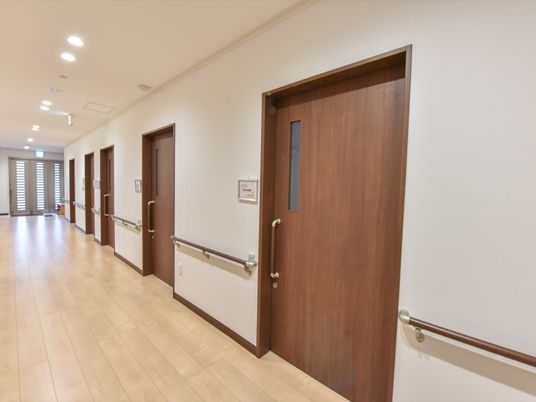 施設の写真 各居室を繋ぐ廊下には側面に手摺りがあり、居室ドアの取っ手も握り易い手摺りタイプ。床はフローリングで車椅子でも移動し易くなっている。